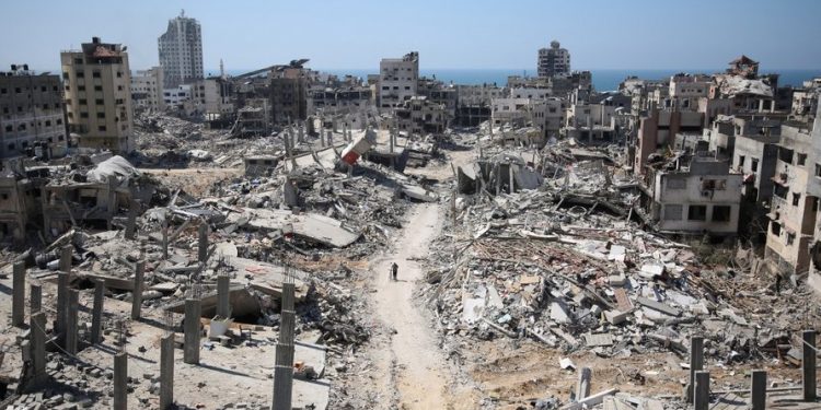 A man pushes a bycicle along as he walks amid building rubble in the devastated area around Gaza's Al-Shifa hospital on April 3, 2024, amid the ongoing conflict between Israel and the Palestinian Hamas militant group. (Photo by AFP)